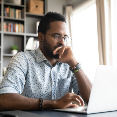 A man with a focused expression using his laptop.