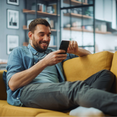 Man on couch smiling at phone