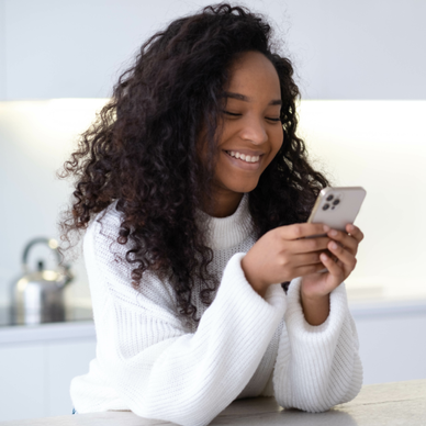 Woman uses a smartphone in her kitchen.