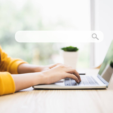A pair of hands typing on a laptop with an abstract search bar in the foreground.