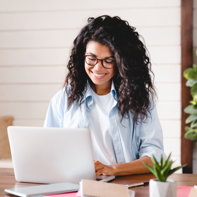 Woman smiles down at her laptop at home.