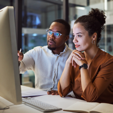 A man and woman sit next to each other and share a computer.  