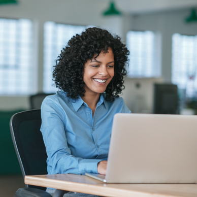 Woman smiles while staring down at her laptop.