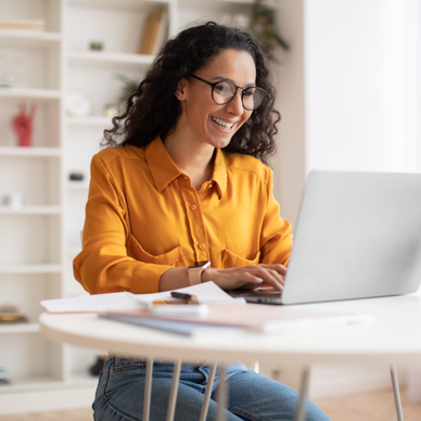 Woman smiles and types on her laptop in her office.