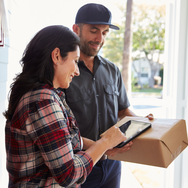 A woman signs for a package in her doorway.