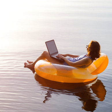 Woman floating on water with laptop