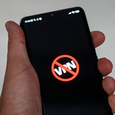 Man holding phone that shows the word "VPN" crossed out because it's been banned.
