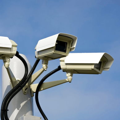 Three surveillance cameras on an outdoor post.