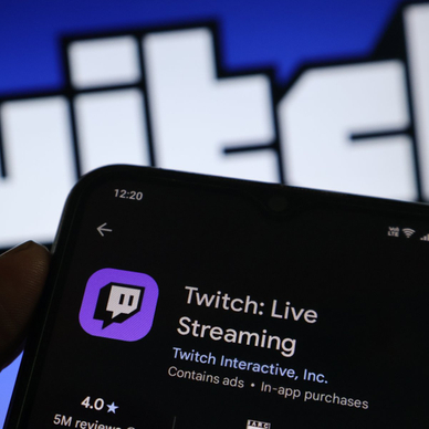 A hand holding a smartphone with the Twitch app open on the screen.
