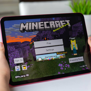 Child holding iPad with Minecraft on screen