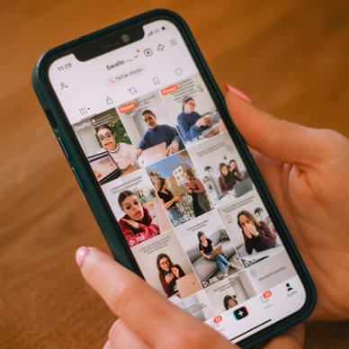 A well-manicured pair of hands holds a phone open to TikTok.