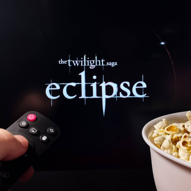 Person watching The Twilight Saga: Eclipse with popcorn and remote control