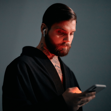 Bearded man in red lighting using a smartphone.