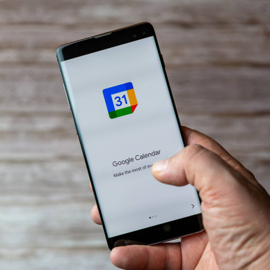 A Mobile phone or cell phone being held showing the Google Calendar app open on screen