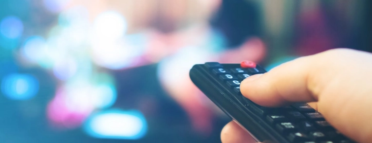 Image of remote being held up to TV